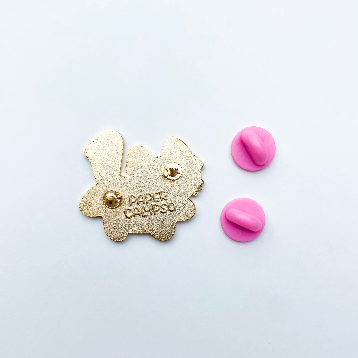 there are two pins on the back for extra security! This way you won't lose your pin if you put it on your clothes or bag. It comes with pretty pink rubber clasps. The back of the pin has a stamp with my watermark and reads "Paper Calypso"