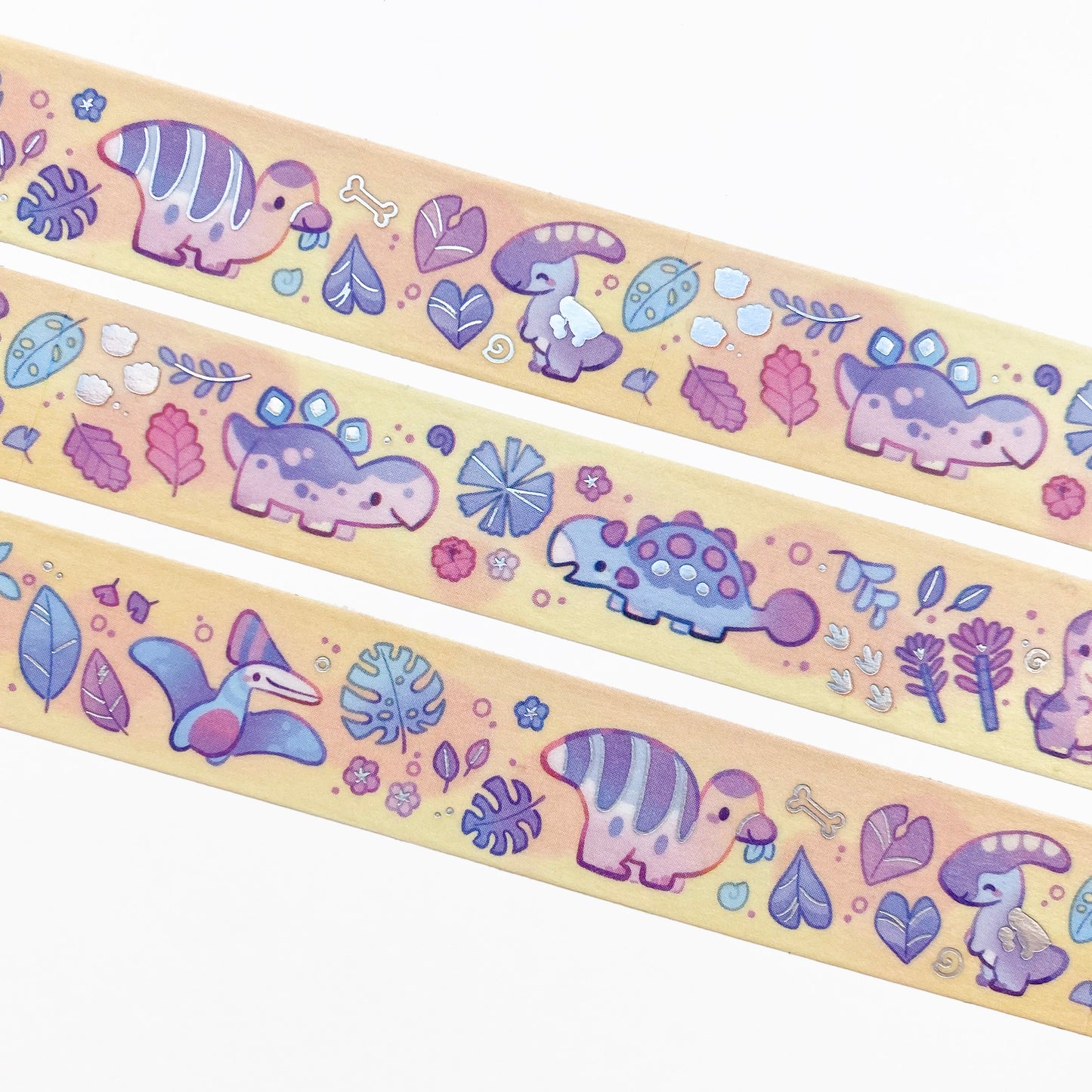 A close-up of the washi tape. Apart from dinosaurs, there are also many plants around the dinosaurs, like ginko leaves, frangipani flowers and ferns. There are also bones, dinosaur footprints and snail shells.