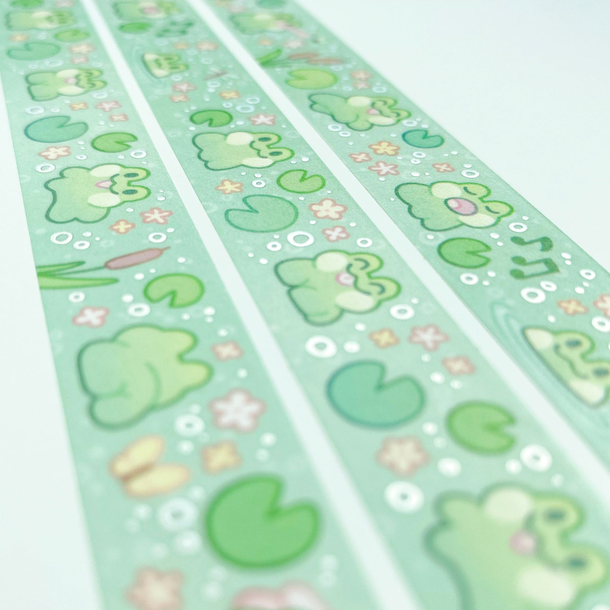 A different angle showing the holographic silver foil reflecting in the light. The foil is used on the bubbles surrounding the frogs, fitting to the wet pond theme.