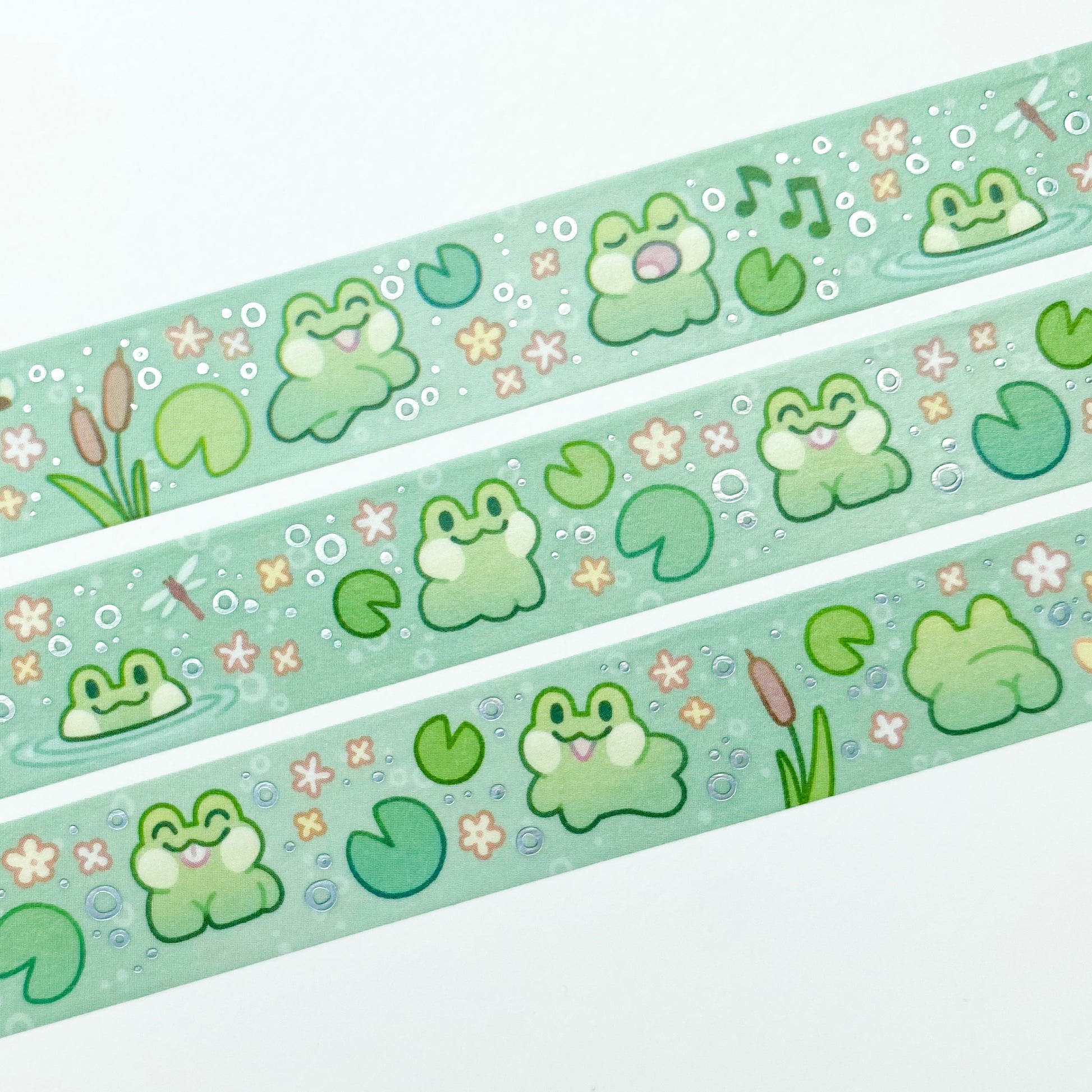 A close-up of the washi tape. The frogs are surrounded by bubbles, dragonflies yellow flowers, lily pads and cattail reeds.