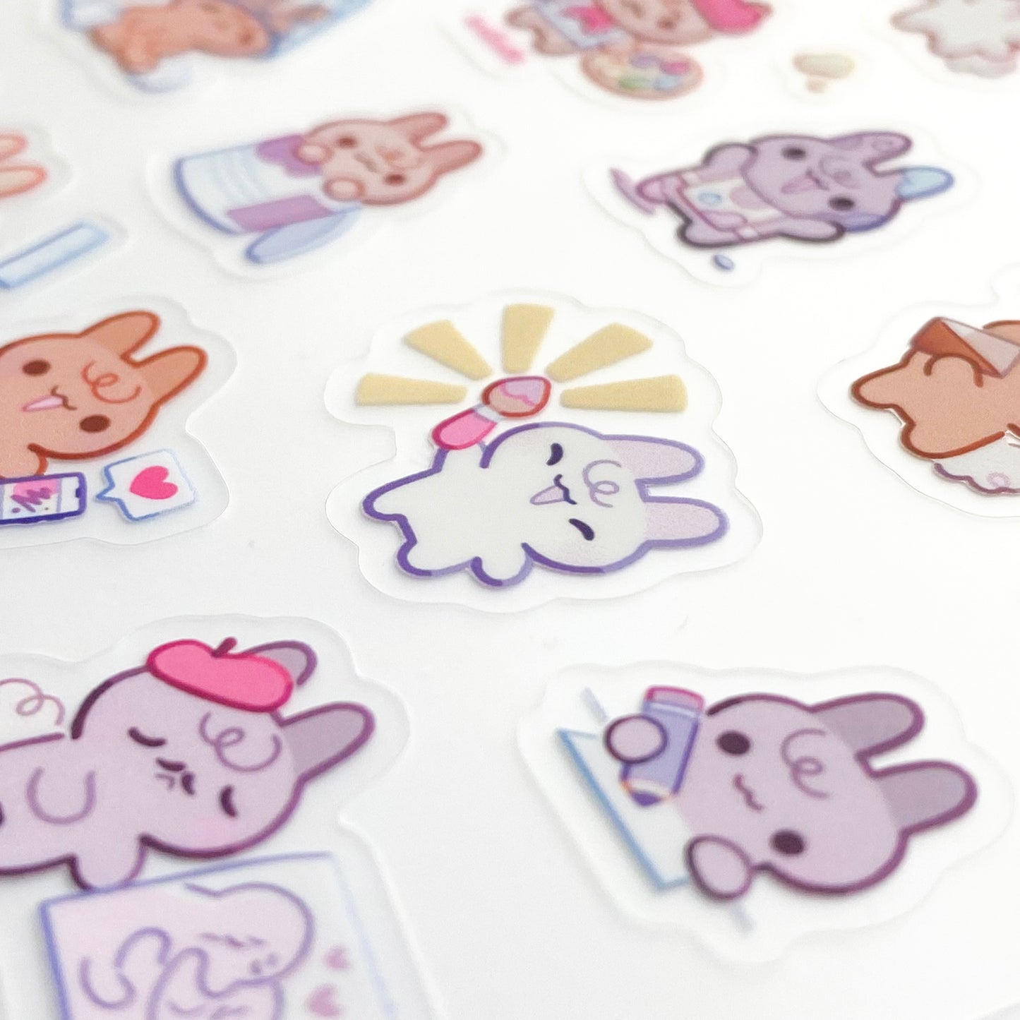 a close-up of the stickers to show the good print quality. In the middle is a bunny proudly holding up a paint brush. Another is drawing with a pencil, two others are full of paint.