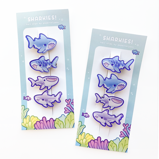 four cute shark hairclips a tiger shark, a great white, a whale shark and a black-tipped reef shark! One purple and one blue set. 