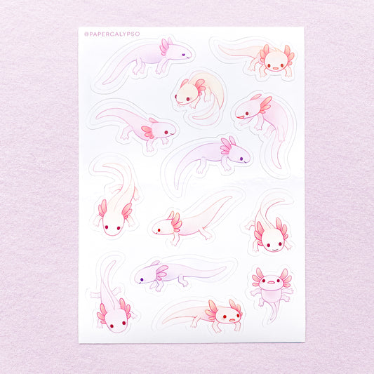 The axolotls are purple, pink and yellow pastel coloured, with little grabby fingers and thick tails. Their gills are stubby, round and cute. Most of them are smiling, while some look a bit stupid and clueless. The sticker sheet has thirteen unique stickers printed on white glossy thin vinyl. This makes them sturdy and waterproof, but not too thick to use in a journal.
