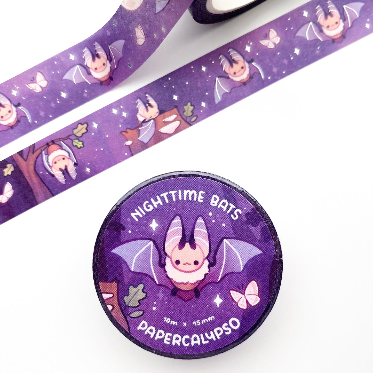 the roll of washi tape is packaged with shrink wrap plastic and a round sticker on one side. On it is a fluffy little bat with it's wings spread out. It reads "Nighttime bats, 10 metres by 15 milimetres, by Papercalypso"