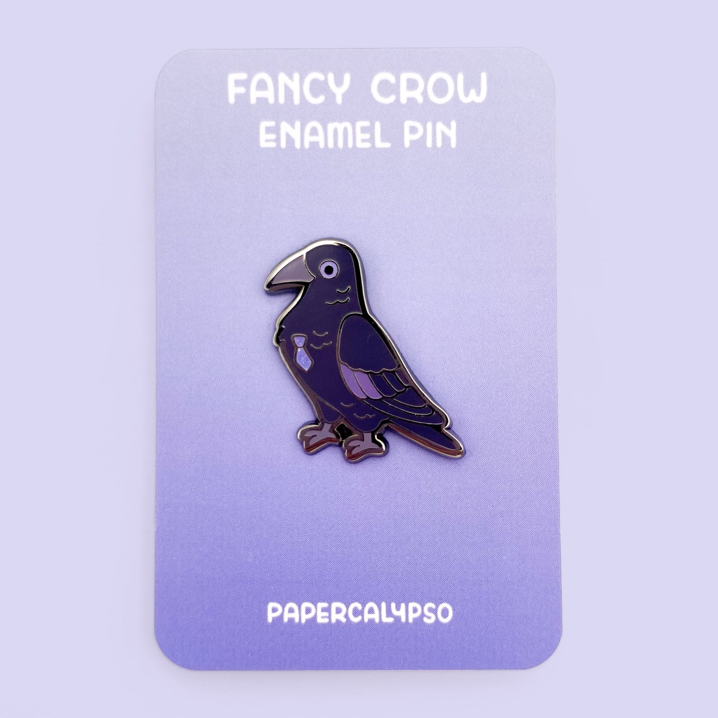 A black nickel hard enamel pin of a crow wearing a glittery purple tie. He's a very fancy individual.