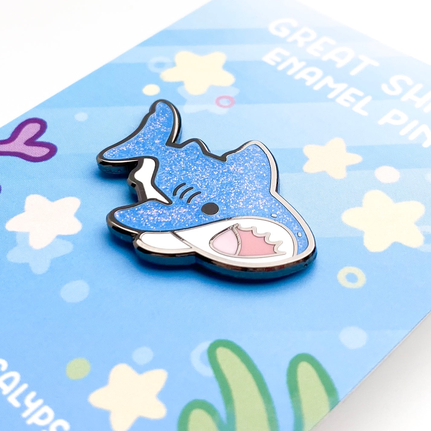 A close-up of the pin so you can see the details. The glitter accents sparkle in the light.  The pin backing features a reef setting with little marine fishy details like stars, bubbles and sea corals.