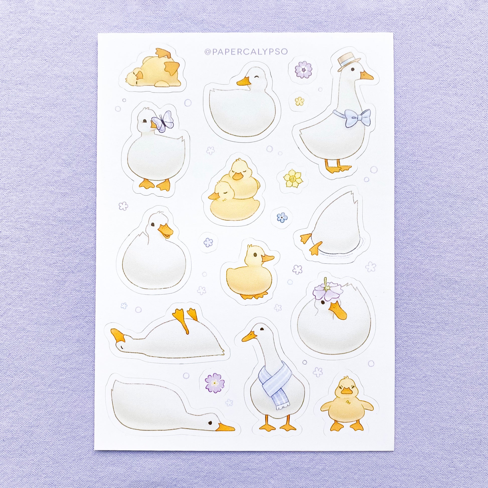 The sticker sheet has yellow baby ducks and grown up white ducks. The line art is thin and light, and the colours are pastel. The sticker sheet has thirteen unique duckling stickers, as well as six smaller flower stickers printed on white matte thin vinyl. This makes them sturdy and waterproof, but not too thick to use in a journal.