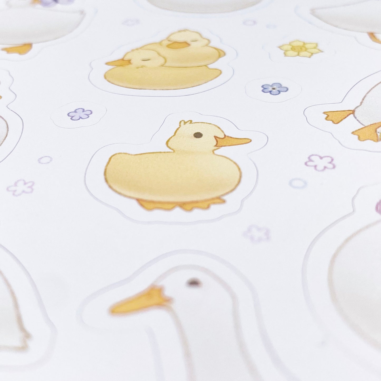 A close-up of the sheet, showing the texture of the matte vinyl and the good print quality. The baby duckling is surrounded by blue and purple spring flowers, as well as daffodils.