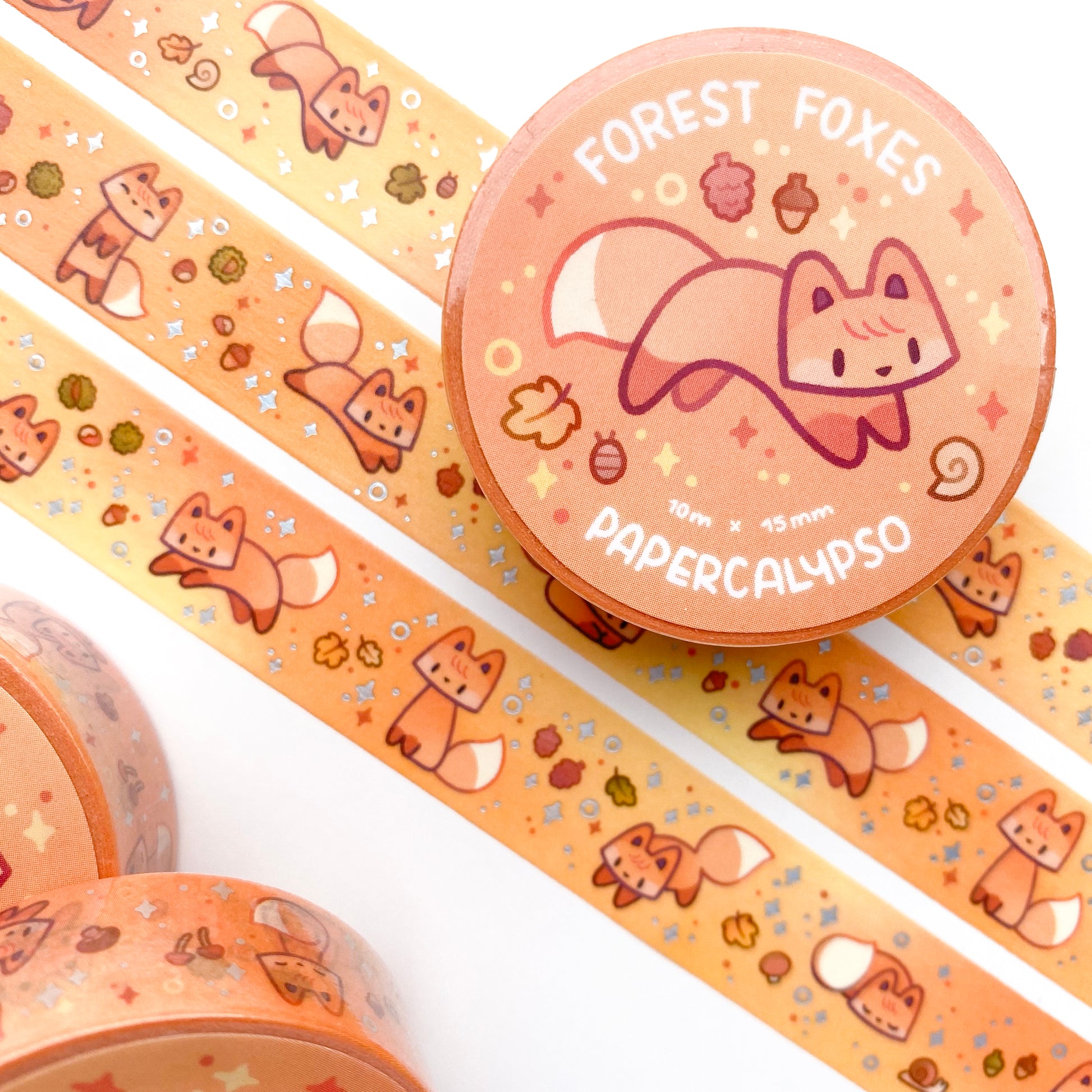 kawaii fox themed washi tape featuring green cartoon foxes on an orange background autumn foliage. These vulpines are jumping around like foxes do while hunting!