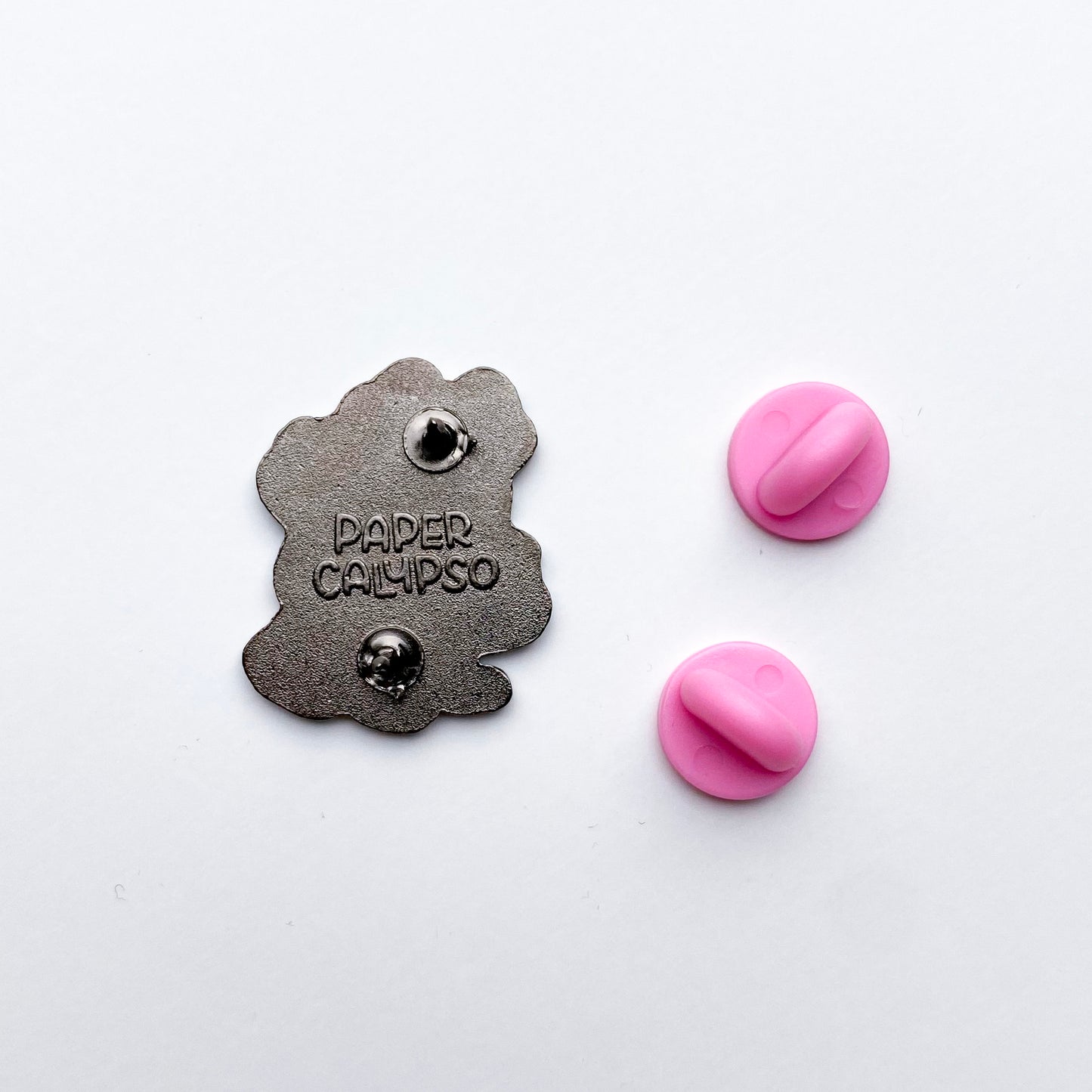 there are two pins on the back for extra security! This way you won't lose your pin if you put it on your clothes or bag. It comes with pretty pink rubber clasps. The back of the pin has a stamp with my watermark and reads "Paper Calypso"