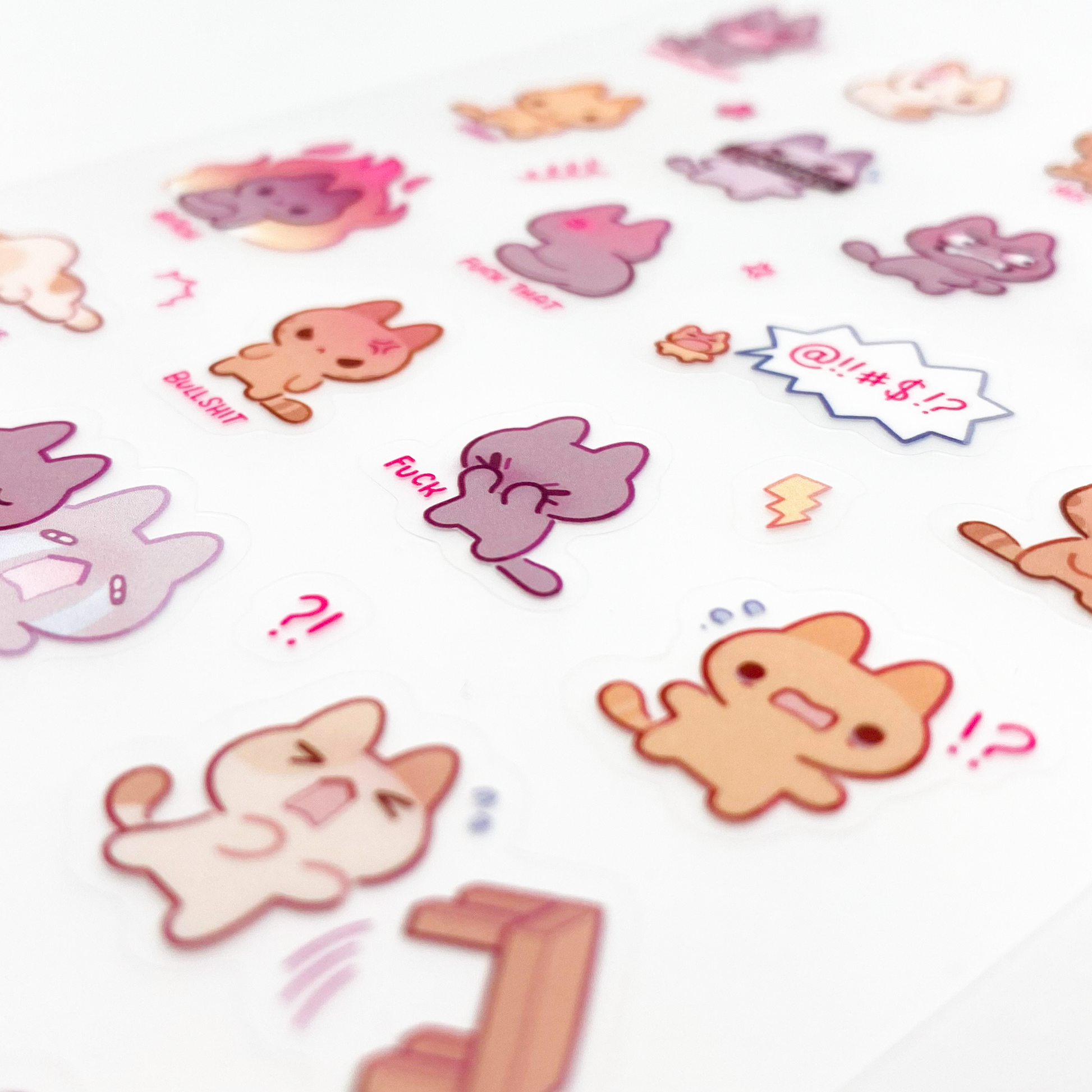 a close-up of the stickers to show the good print quality. In the middle is a cat face-palming and swearing. Underneath it is another one flipping a table. There's even one so angry, it's on fire.
