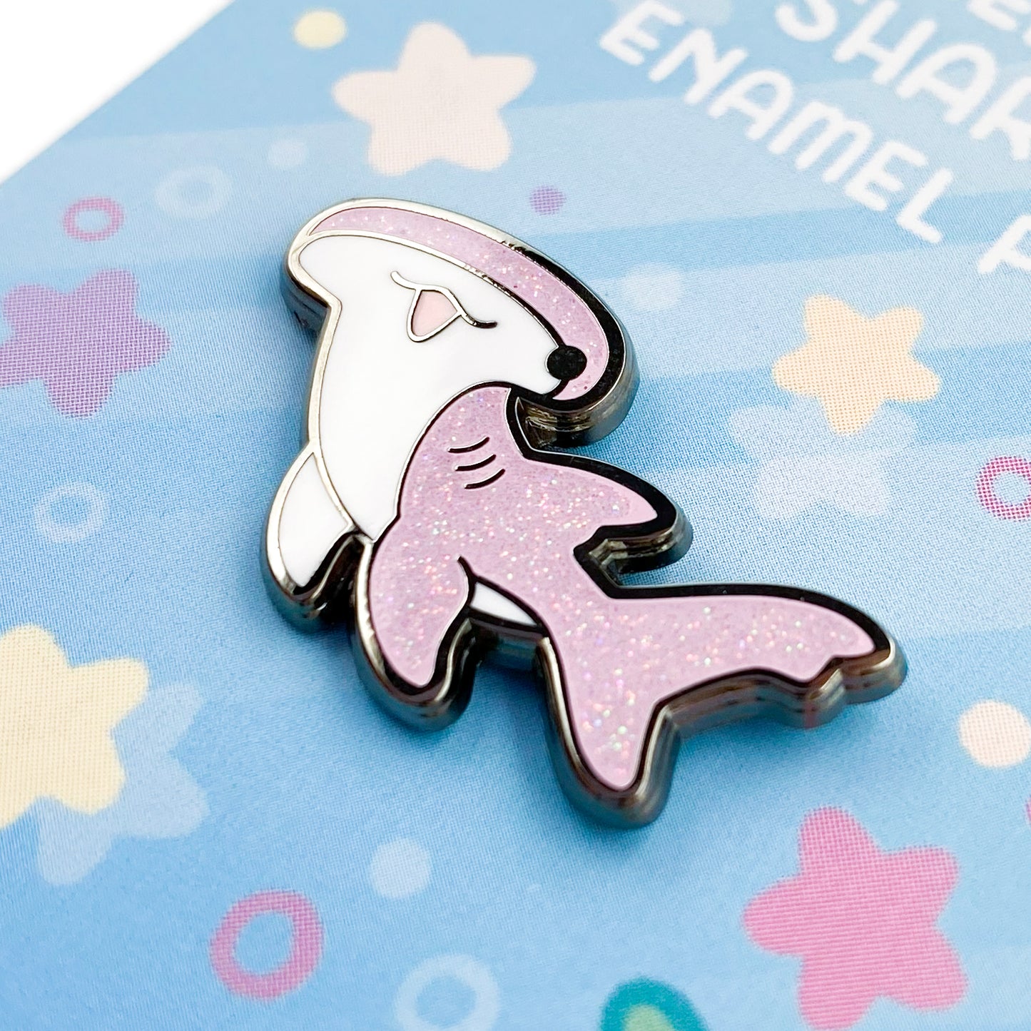 A close-up of the pin so you can see the details. The glitter accents sparkle in the light.  The pin backing features a reef setting with little marine fishy details like stars, bubbles and sea corals.