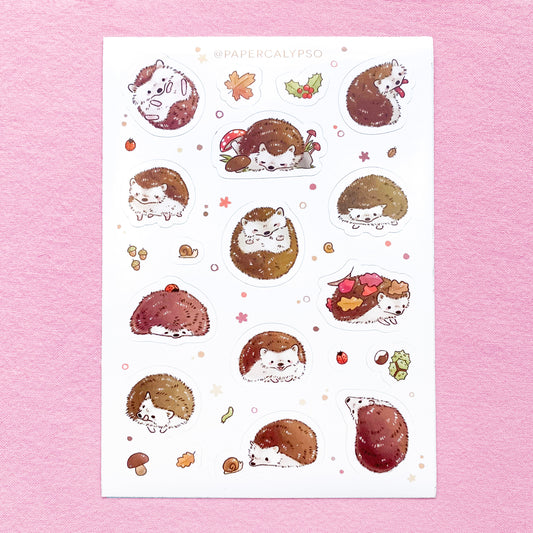 The hedgehogs are brown with beige underbellies. They have small faces and little blush spots. Around them is autumn themed foliage and creepy crawlies, like acorns, chestnuts, snails, holly, mushrooms and caterpillars. The sticker sheet has thirteen unique hedgehog stickers and eight smaller autumn stickers printed on white glossy thin vinyl. This makes them sturdy and waterproof, but not too thick to use in a journal.