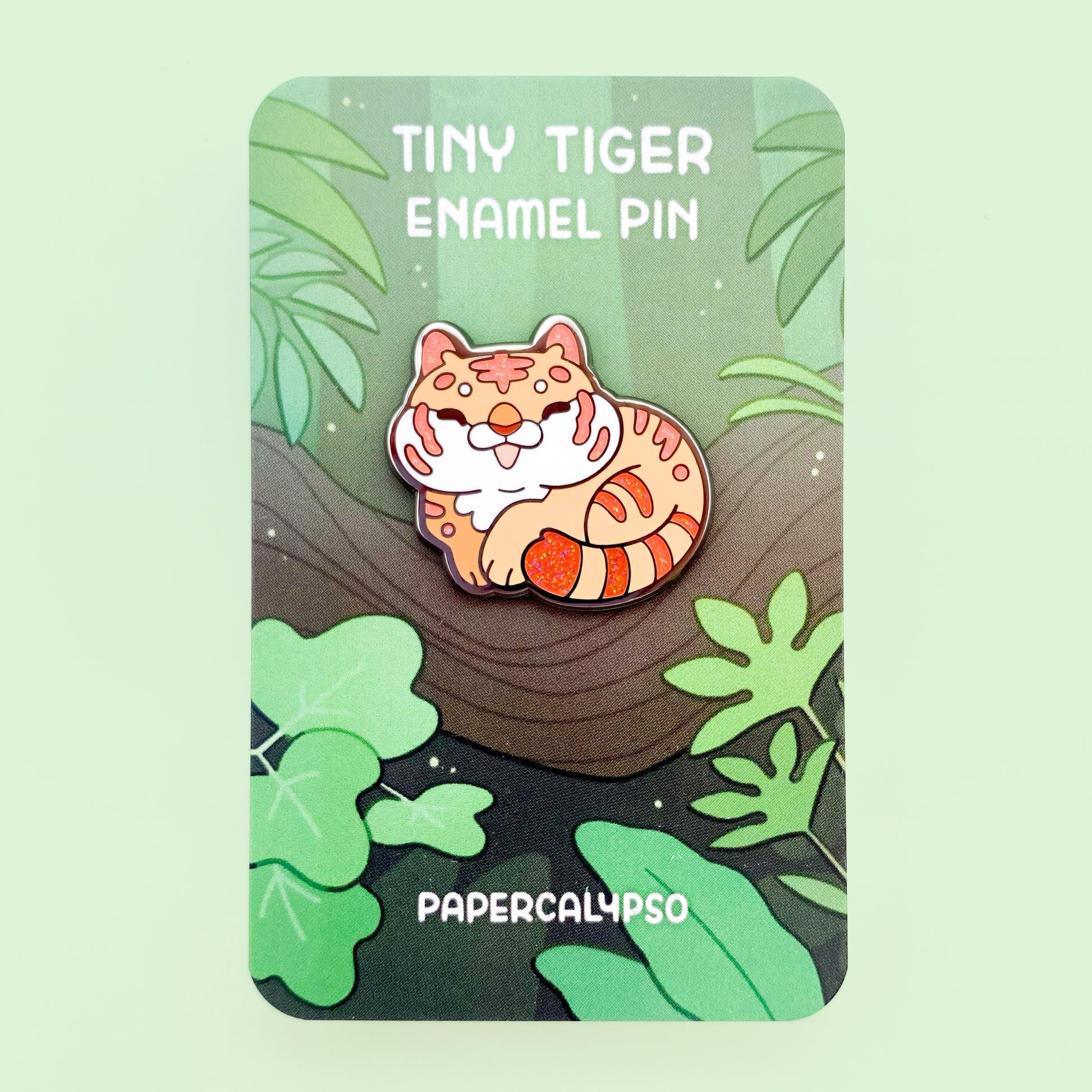 A black nickel plated hard enamel pin of a cartoon feline tiger with glittery orange stripes.
