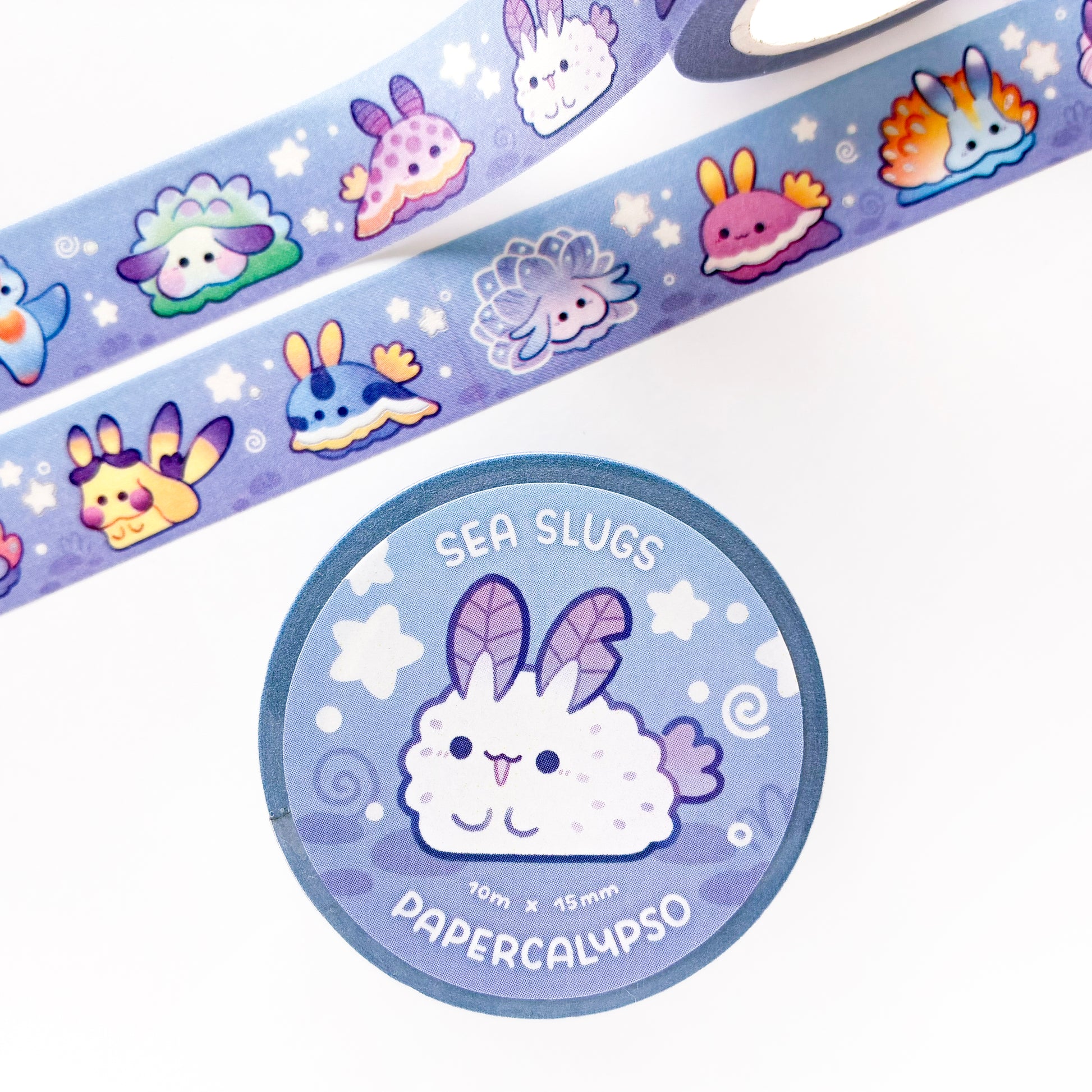 the roll of washi tape is packaged with shrink wrap plastic and a round sticker on one side. On it is an adorable sea bunny surrounded by stars and swirls. It reads "Sea Slugs, 10 metres by 15 milimetres, by Papercalypso"