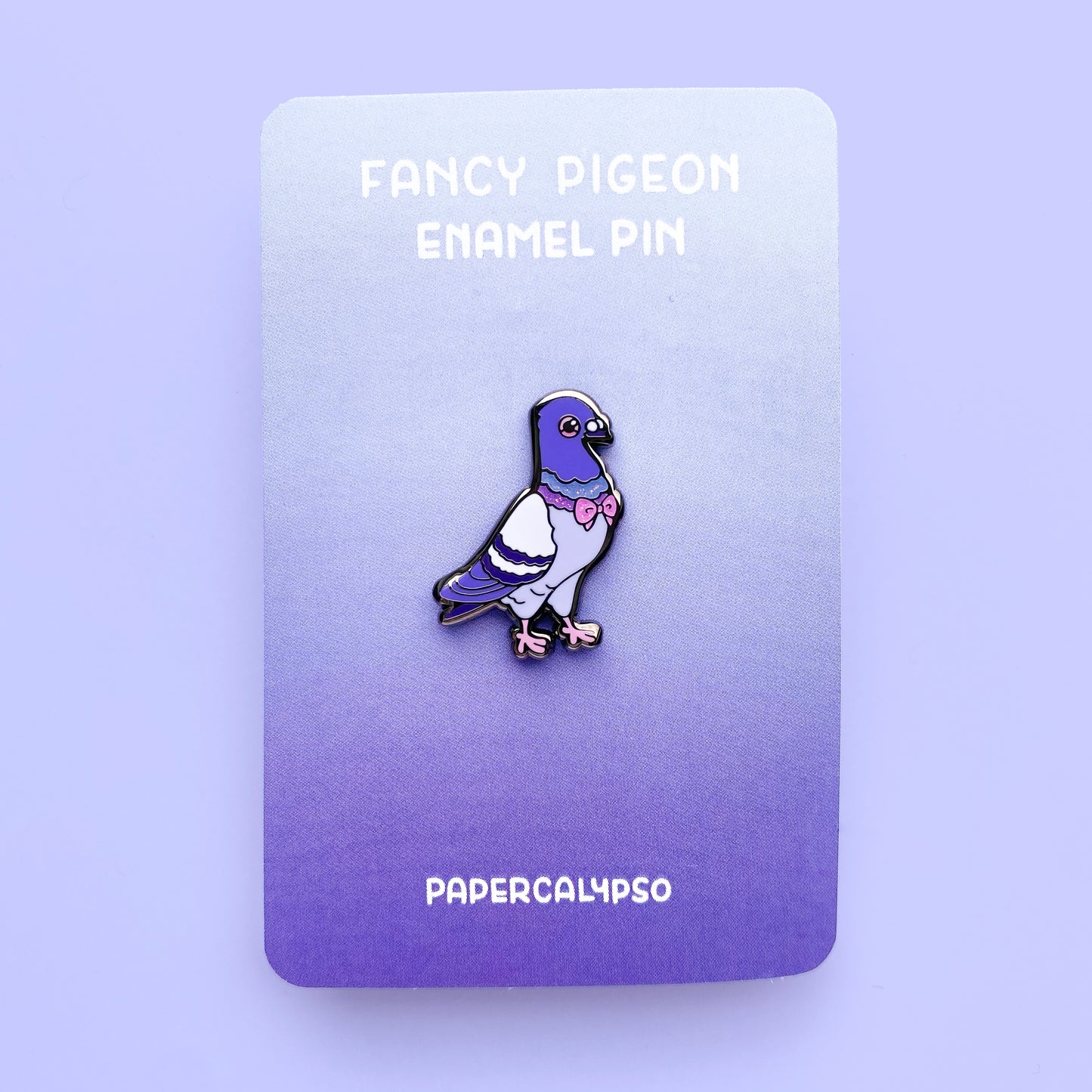 A black nickel hard enamel pin of a purple pigeon proudly presenting his sparkly glitter bowtie. He's mainly purple with some glittery green and purple accents around his neck. His eyes and feet are pink.