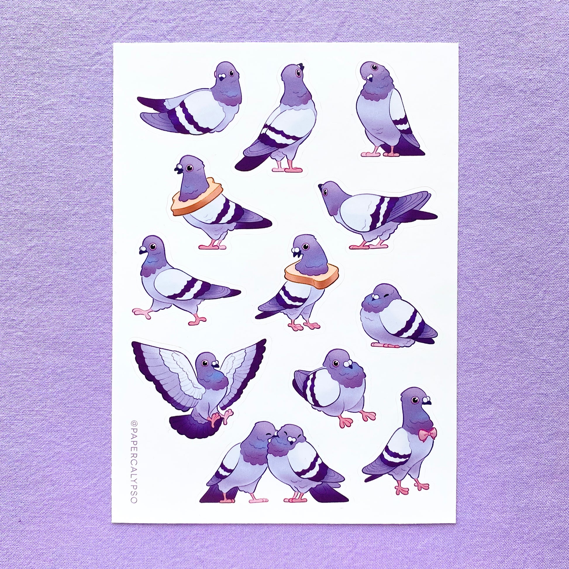 The pigeons are in purple pastel colours with some green and pink on their necks. Their eyes and feet are pink. The sticker sheet has 12 unique stickers printed on white glossy thin vinyl. This makes them sturdy and waterproof, but not too thick to use in a journal.