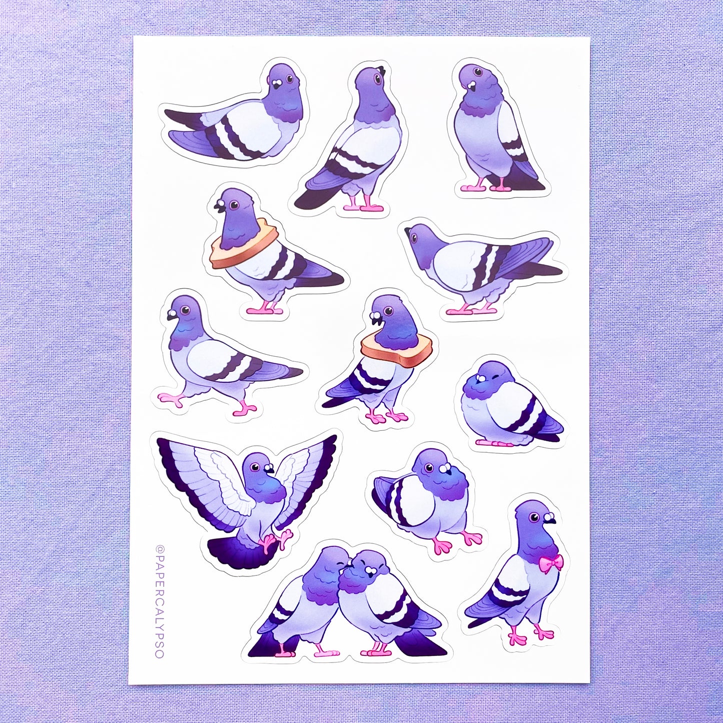The pigeons are in purple pastel colours with some green and pink on their necks. Their eyes and feet are pink. The sticker sheet has 12 unique stickers printed on white glossy thin vinyl. This makes them sturdy and waterproof, but not too thick to use in a journal.