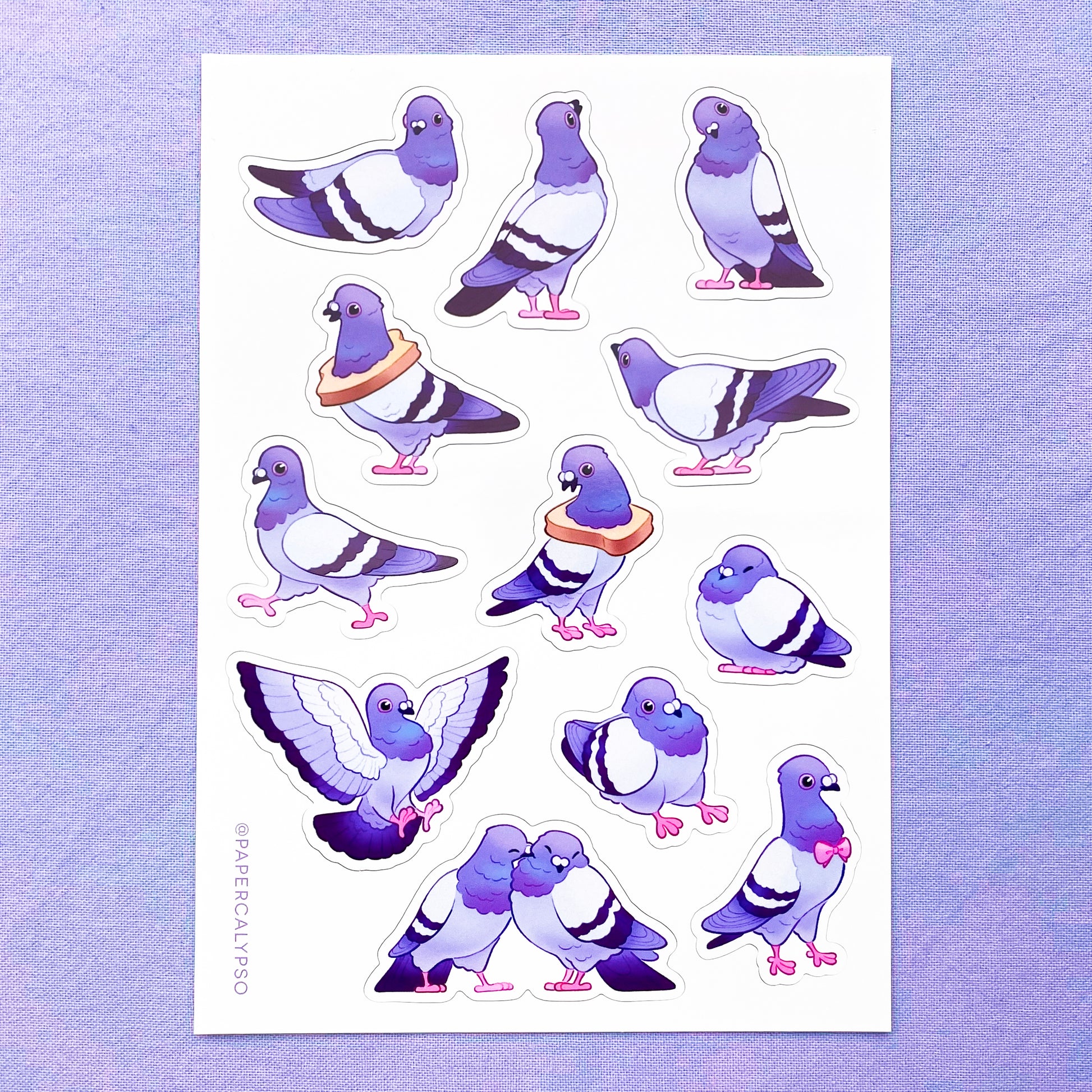 The pigeons are in purple pastel colours with some green and pink on their necks. Their eyes and feet are pink. The sticker sheet has 12 unique stickers printed on white glossy thin vinyl. This makes them sturdy and waterproof, but not too thick to use in a journal.