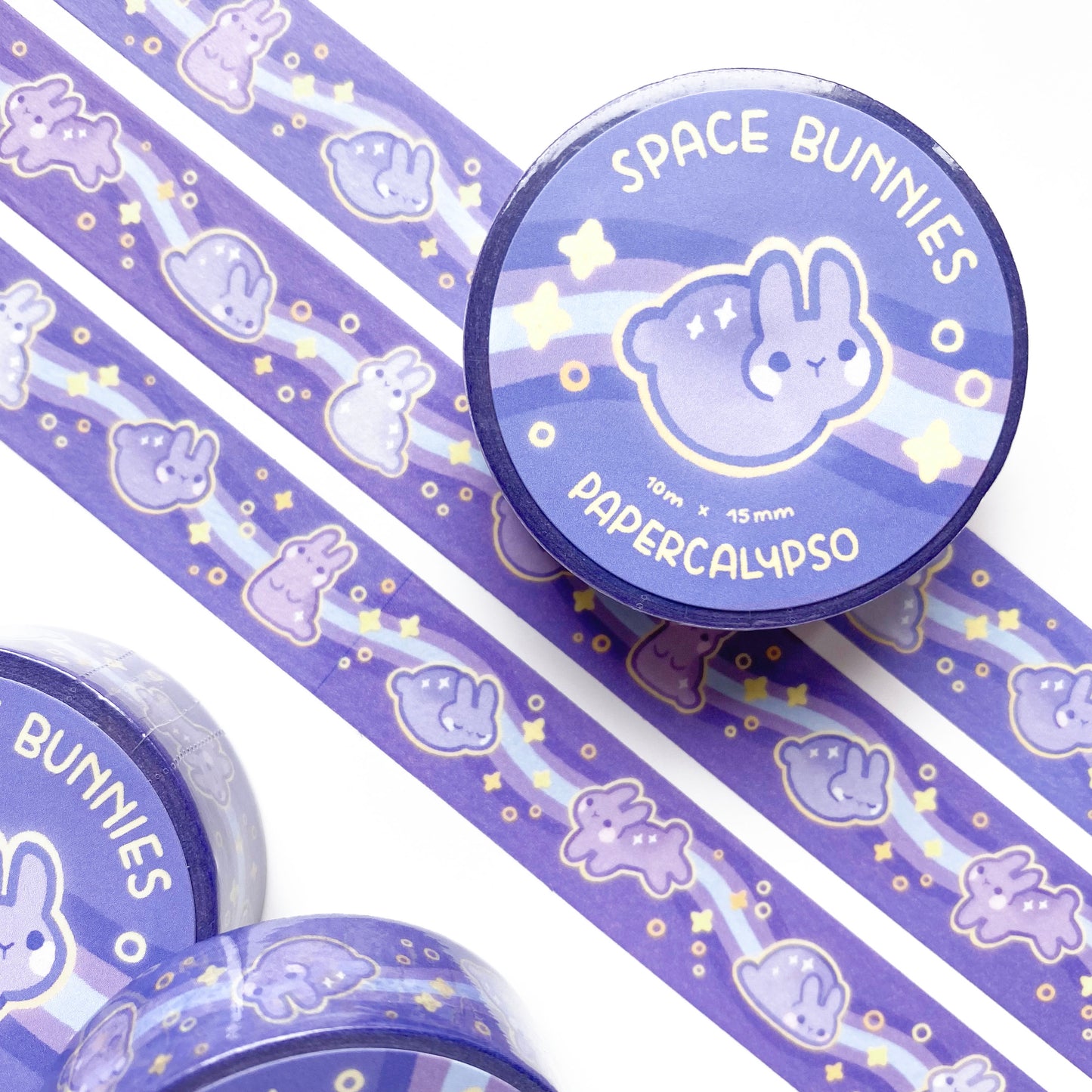 kawaii bunny themed washi tape featuring purple cartoon rabbits on a purple background with stars and swirls. The buns are made of stardust and surrounded by a yellow glow.