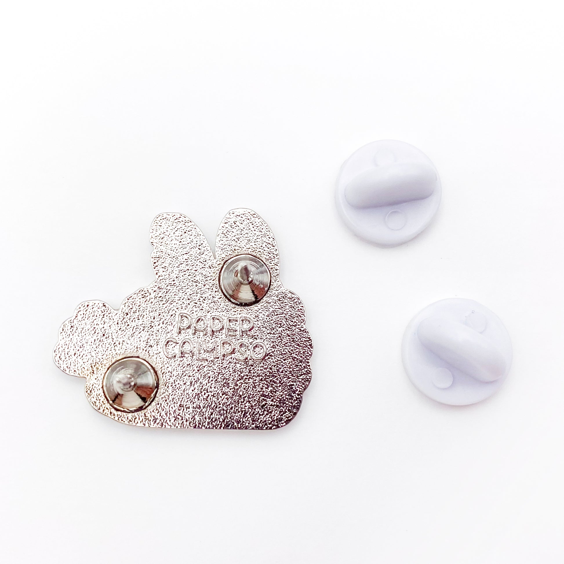 there are two pins on the back for extra security! This way you won't lose your pin if you put it on your clothes or bag. It comes with white rubber clasps. The back of the pin has a stamp with my watermark and reads "Paper Calypso"