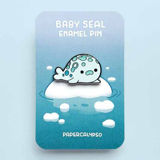 A black nickel hard enamel pin of a little spotted harbor seal. He's so fat, he's almost a circle. He's looking at you with a cute face! 1
