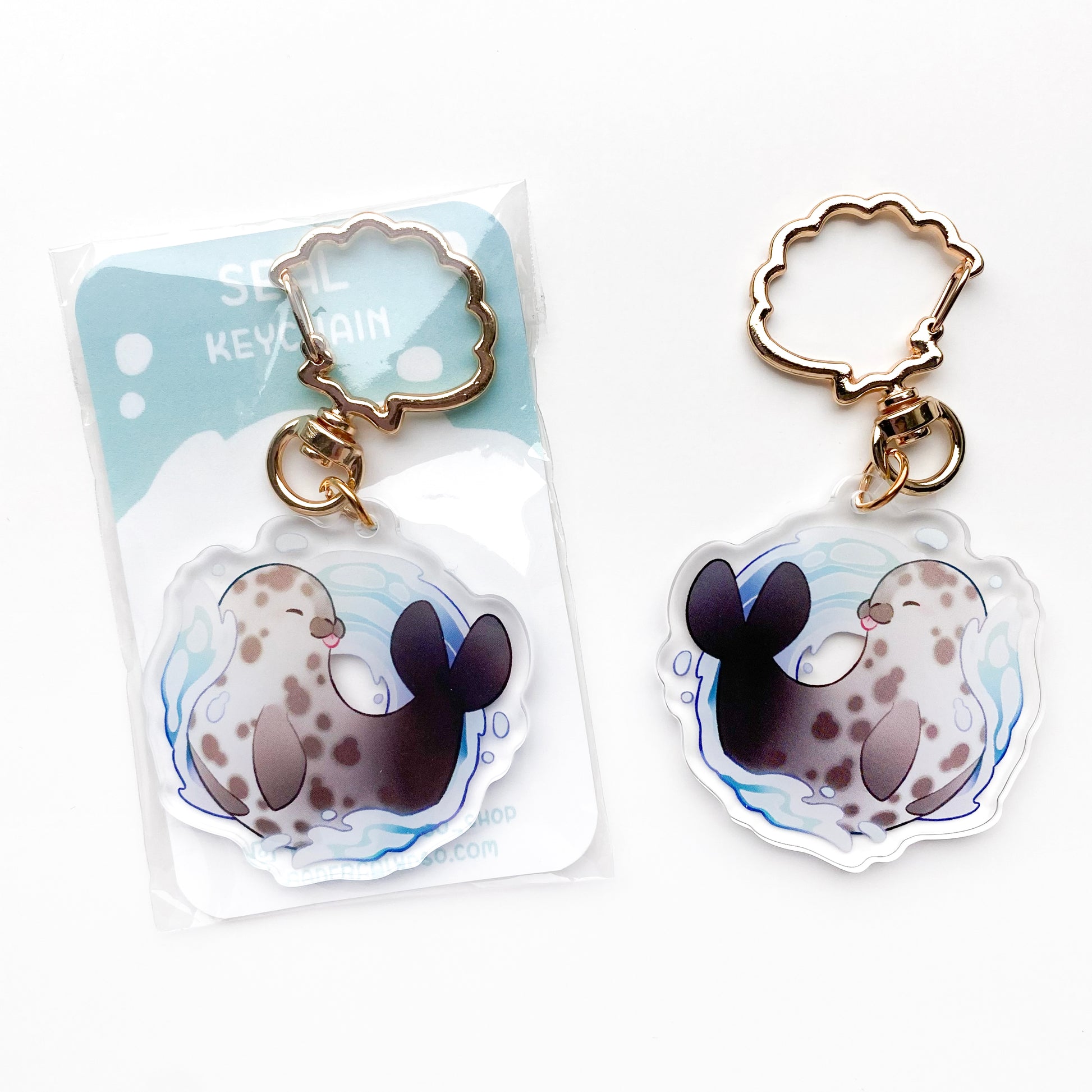 A cute drawing of a chunky seal, posing in the water. It's a spotted common harbor seal, holding its fins to its body and sticking out its tongue. The sea water is a pretty blue colour and splashing everywhere.