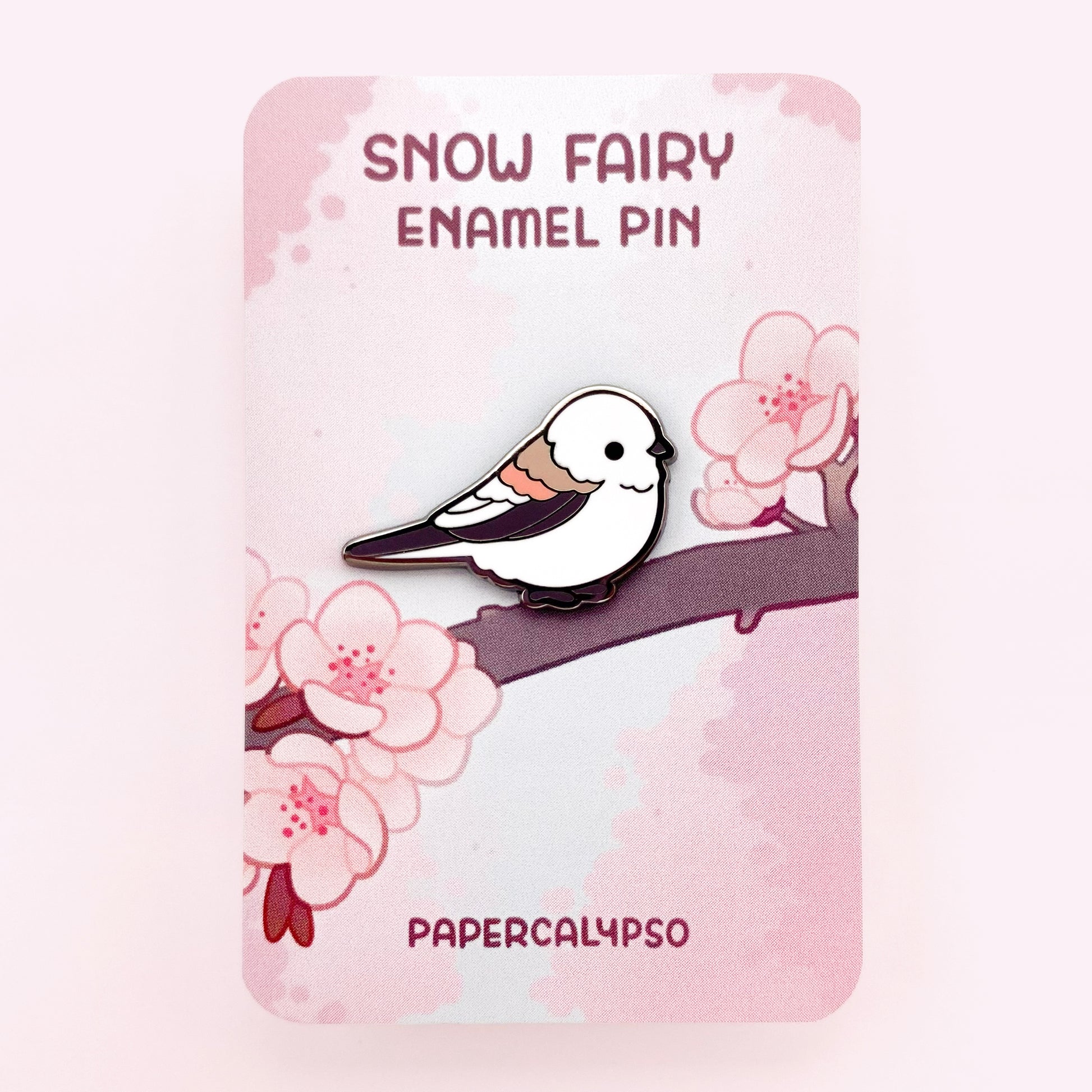 Snow fairy black nickel enamel pin on a backing card with Japanese pink cherry blossoms.
