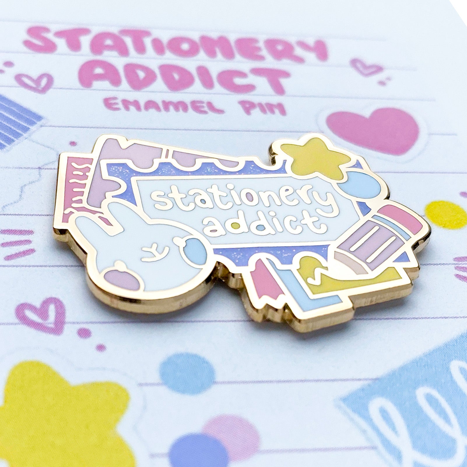 a close-up of the pin to better show the quality. The enamel is nice and smooth. The backing card is looks like a piece of notebook paper that's been drawn on and has stickers, washi tape and confetti stuck to it. To keep the pin scratch-free, the pins are packaged in cellophane baggies.