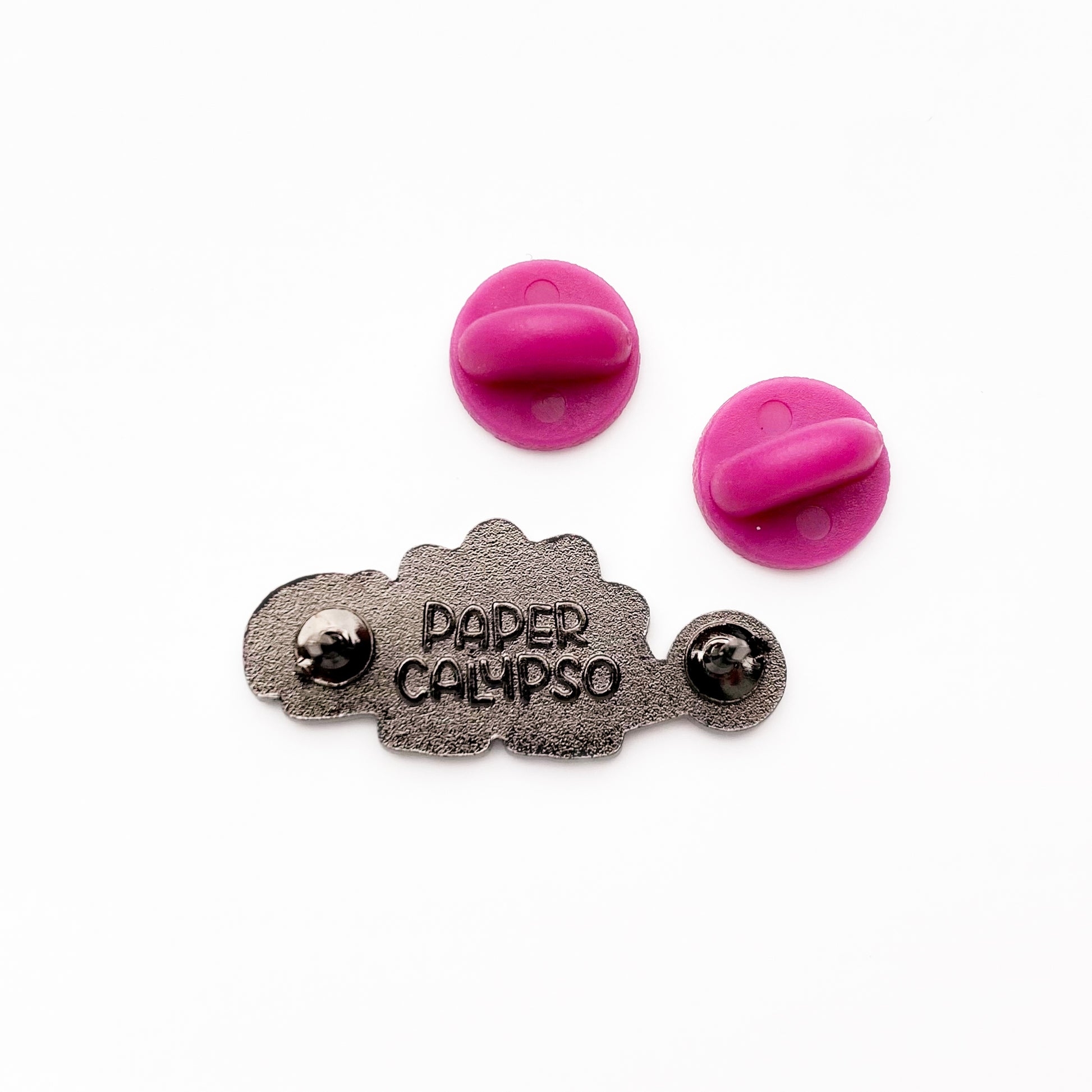 there are two pins on the back for extra security! This way you won't lose your pin if you put it on your clothes or bag. It comes with pink rubber clasps. The back of the pin has a stamp with my watermark and reads "Paper Calypso"