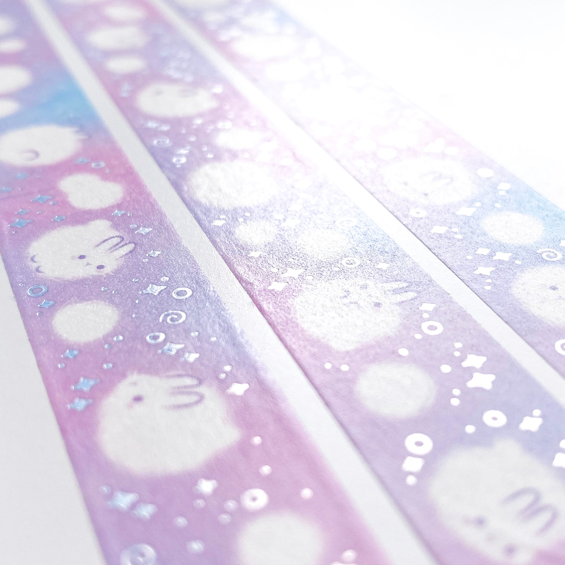 A different angle showing the silver foil reflecting in the light. The foil is used on little swirls and sparkles surrounding the bunnies, giving the washi tape a magical feeling.