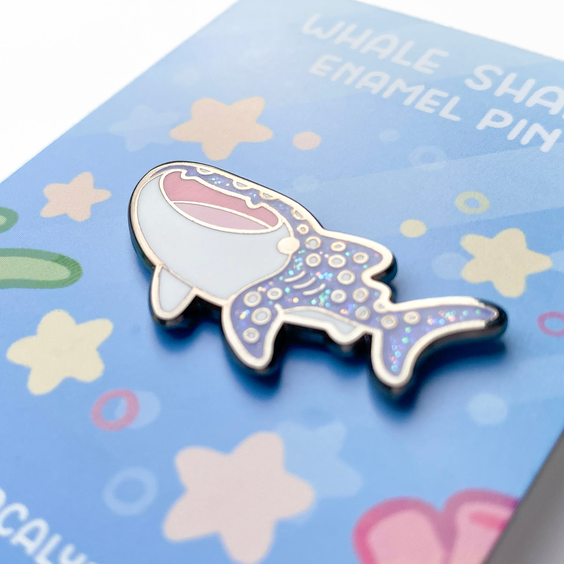 A close-up of the pin so you can see the details. The glitter accents sparkle in the light.  The pin backing features a reef setting with little marine fishy details like stars, bubbles and sea corals.